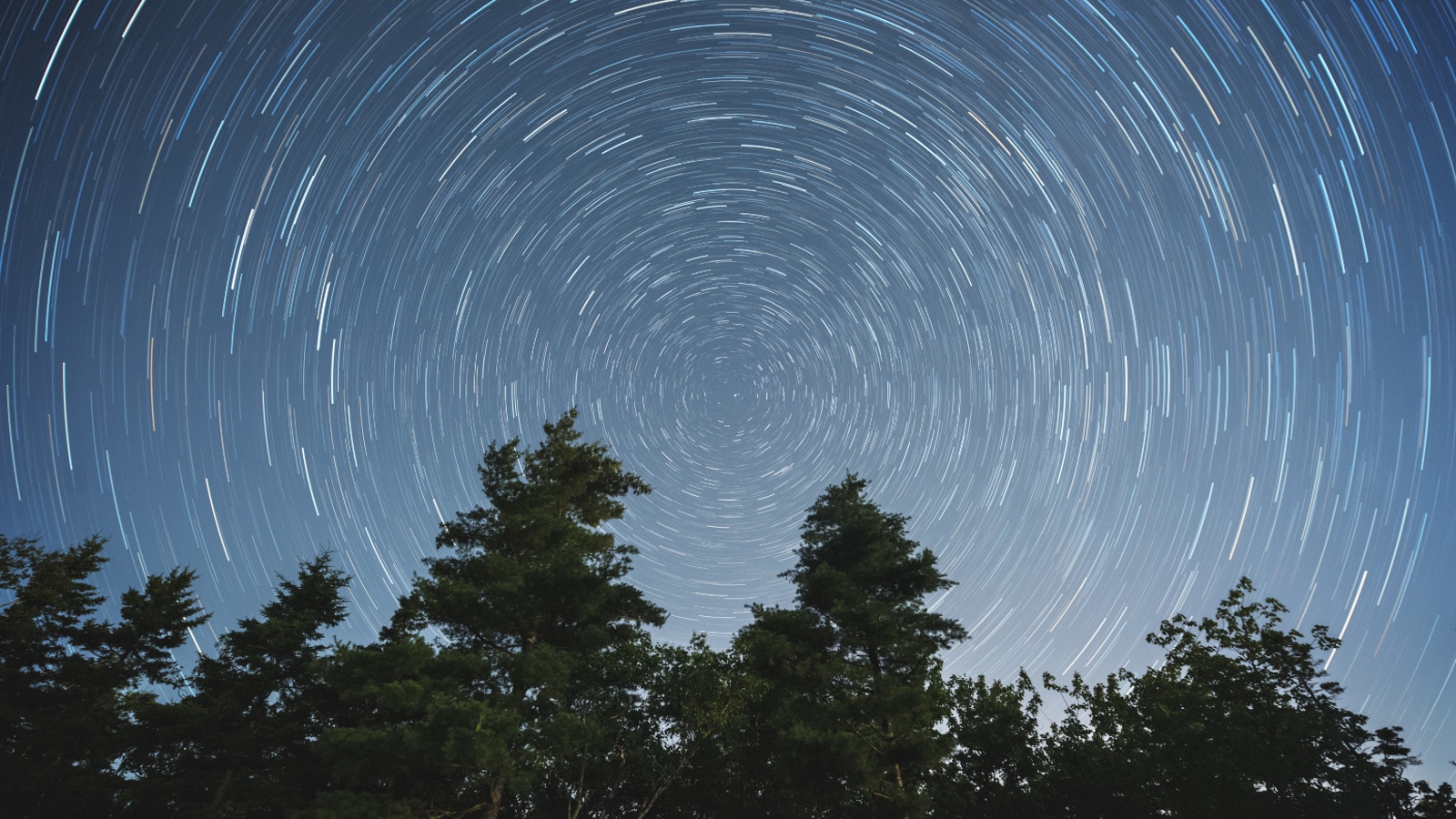 Traînées d'étoiles en spirale dans le ciel nocturne causées par la rotation de la Terre