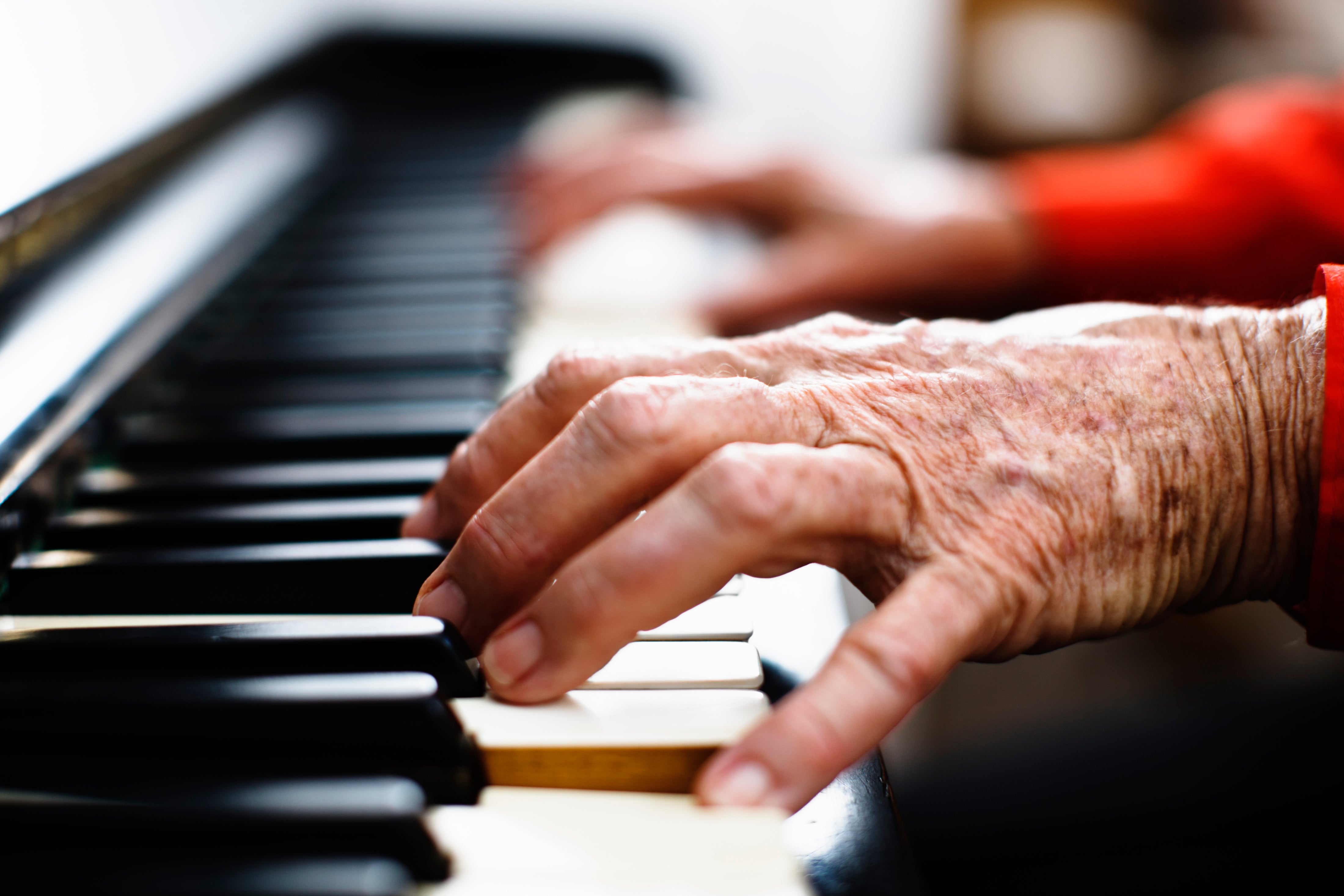 Vieilles mains ridées avec des poignets rouges jouant du piano.