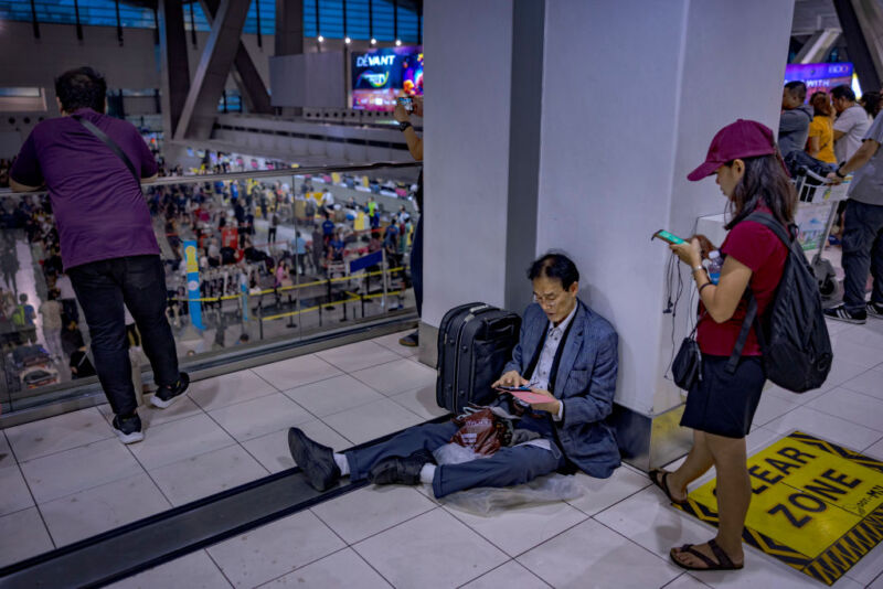 Un passager assis par terre alors que de longues files d'attente se forment aux comptoirs d'enregistrement à l'aéroport international Ninoy Aquino, le 19 juillet 2024 à Manille, Philippines.