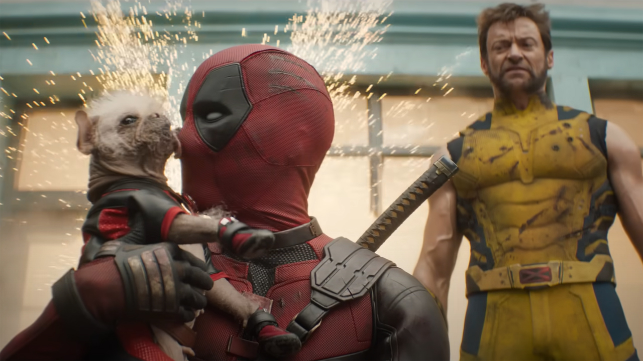 Dogpool lèche le visage de Deadpool pendant que Wolverine observe dans Deadpool et Wolverine