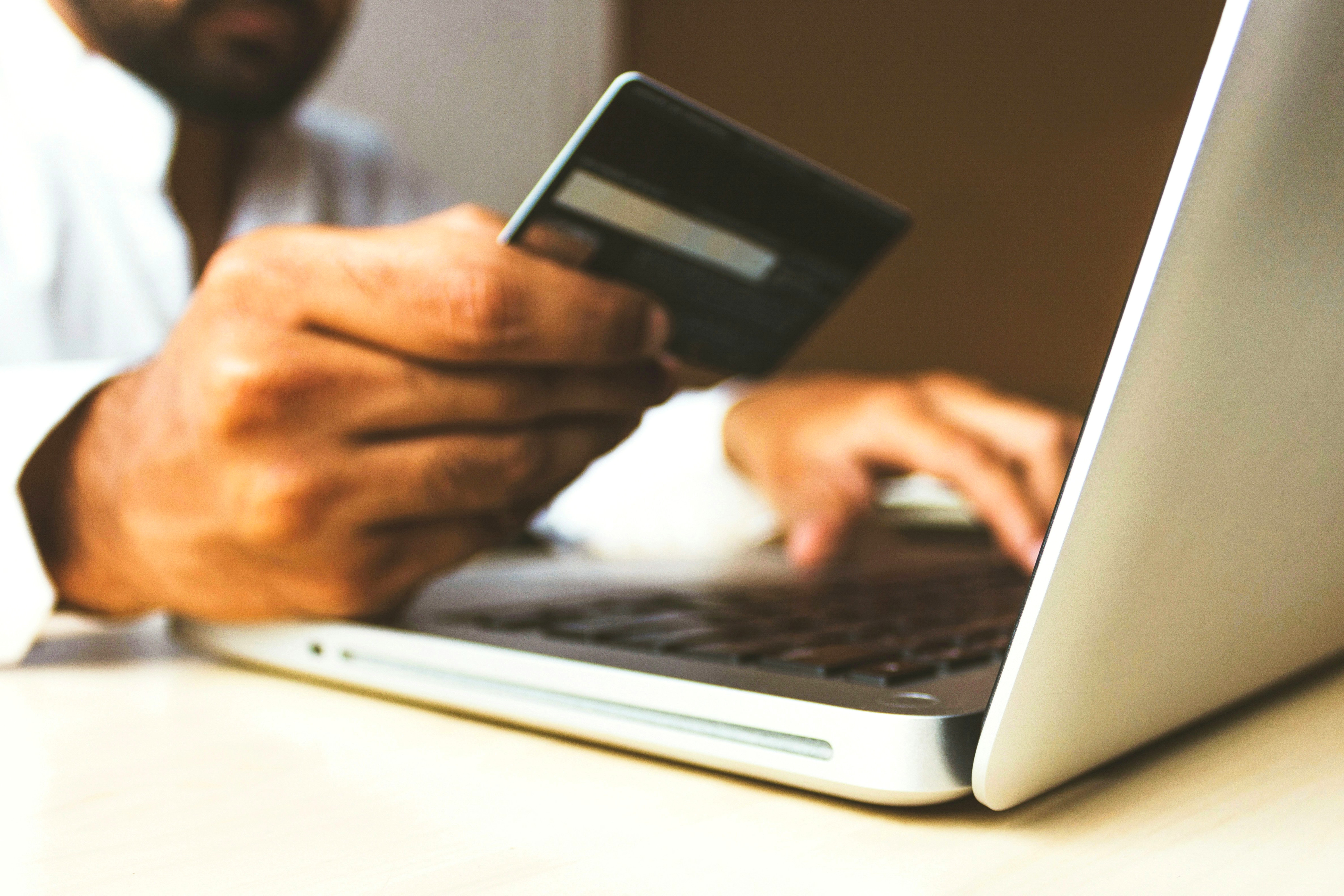 Homme sur un ordinateur portable tenant une carte de crédit pour un achat en ligne