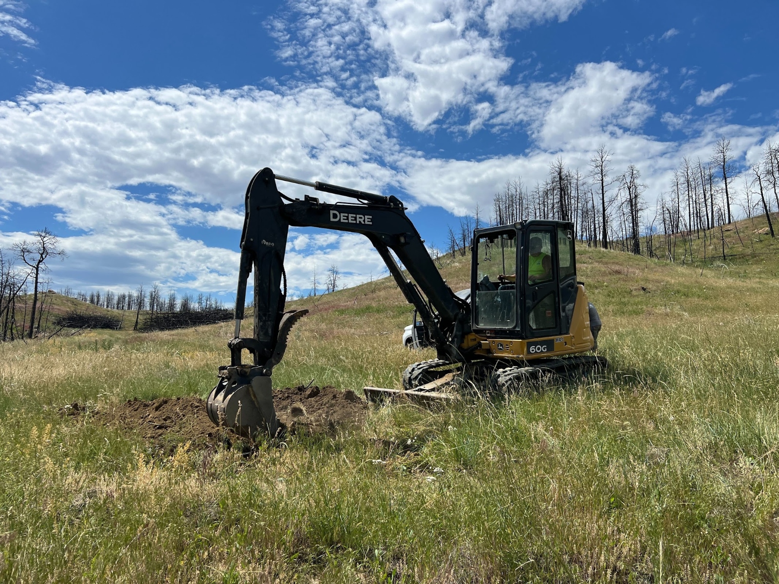 Des machines lourdes préparent le sol pour un projet d'enfouissement de bois dans un champ herbeux