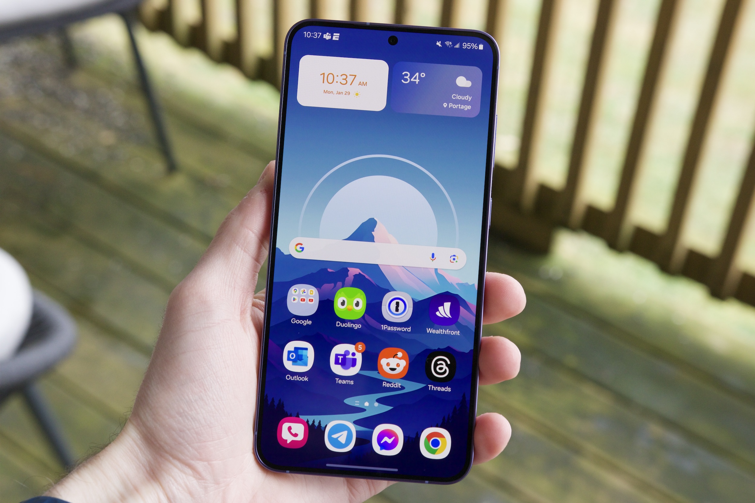 Une personne tenant le Samsung Galaxy S24 Plus avec son écran allumé.