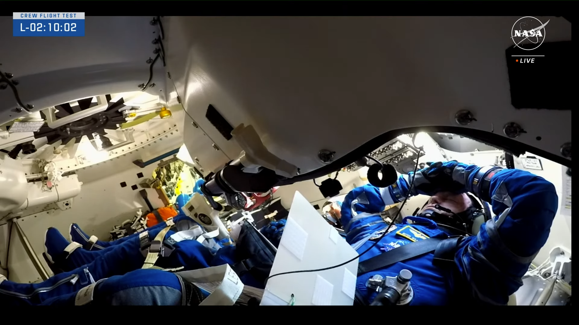 Deux astronautes en combinaisons bleues attendent le lancement à l'intérieur de leur capsule Starliner de Boeing.