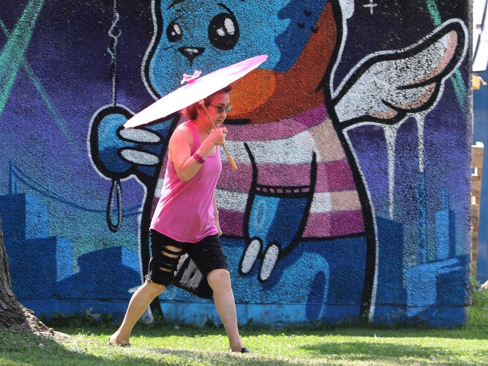 Une femme cherche un peu de répit sous un petit parapluie à Britannia Beach.