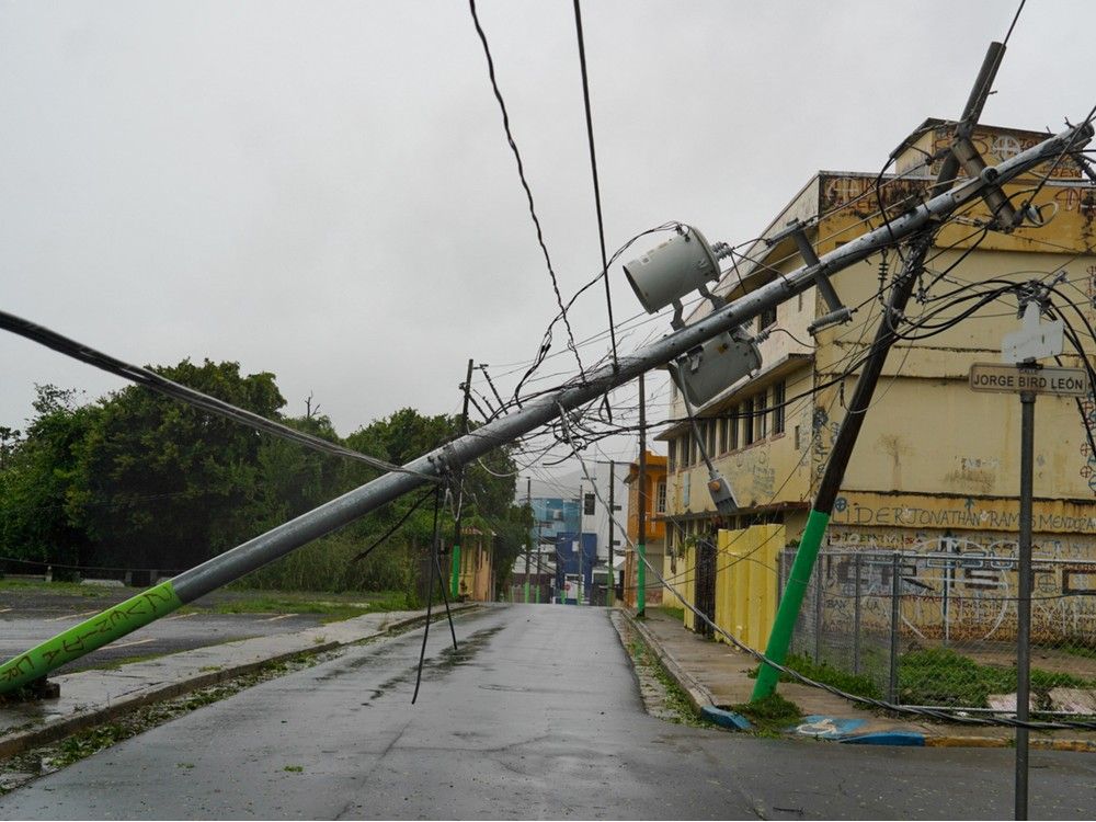 actualités Un poteau électrique est tombé sur une rue, avec un bâtiment jaune en arrière-plan.