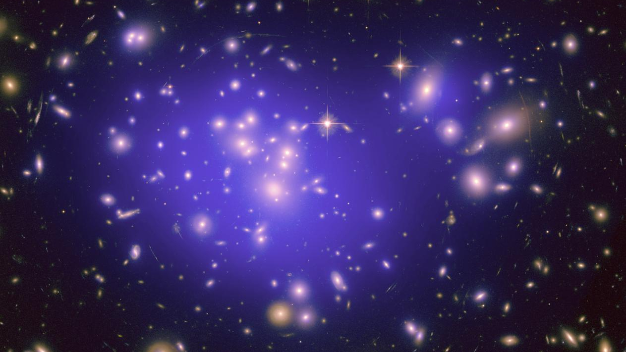 photo scientifique de l'espace profond montrant des dizaines de galaxies, entourées d'une lueur violette