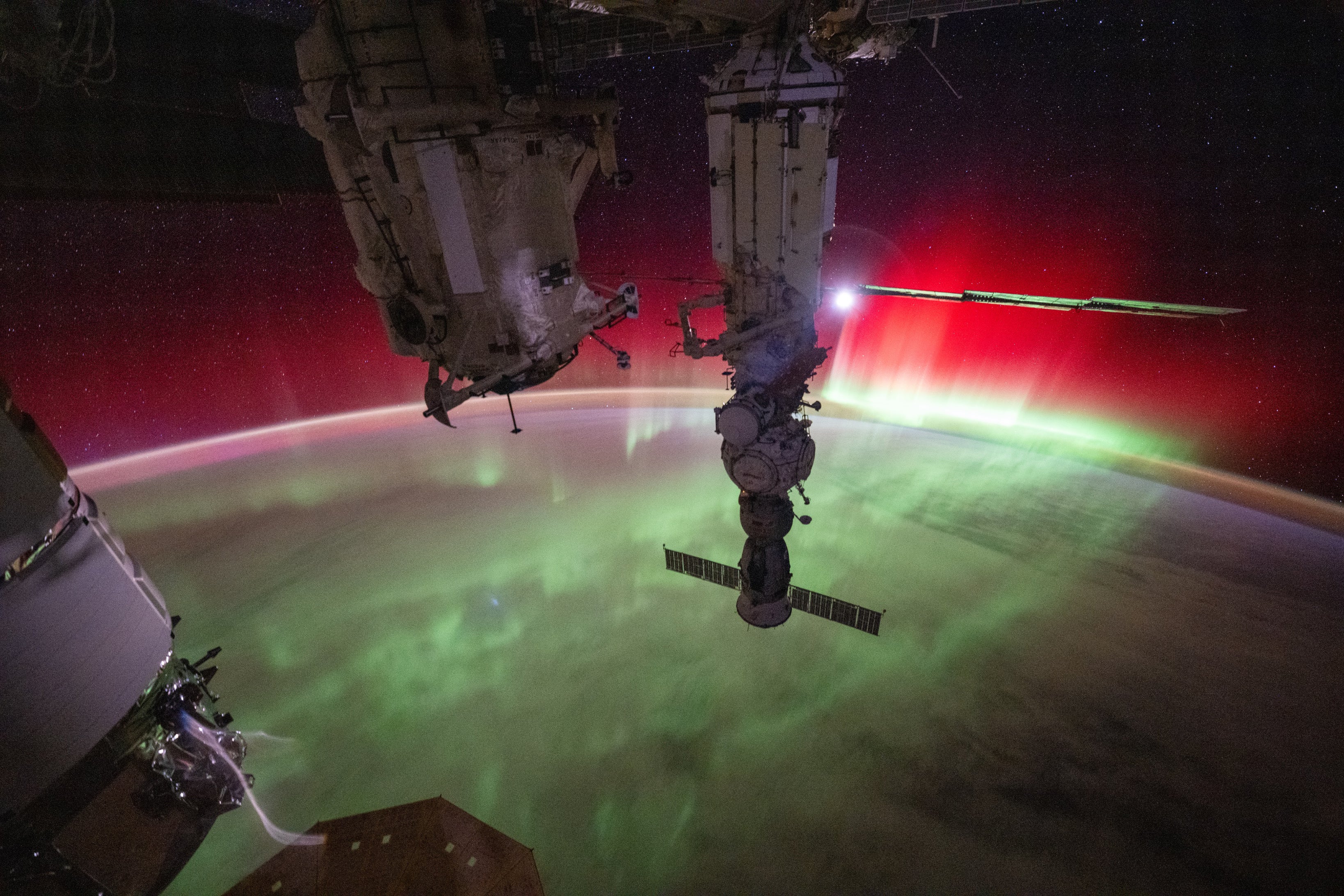 science Une aurore lumineuse verte et rouge couronne la Terre, avec des parties de la Station Spatiale Internationale au premier plan