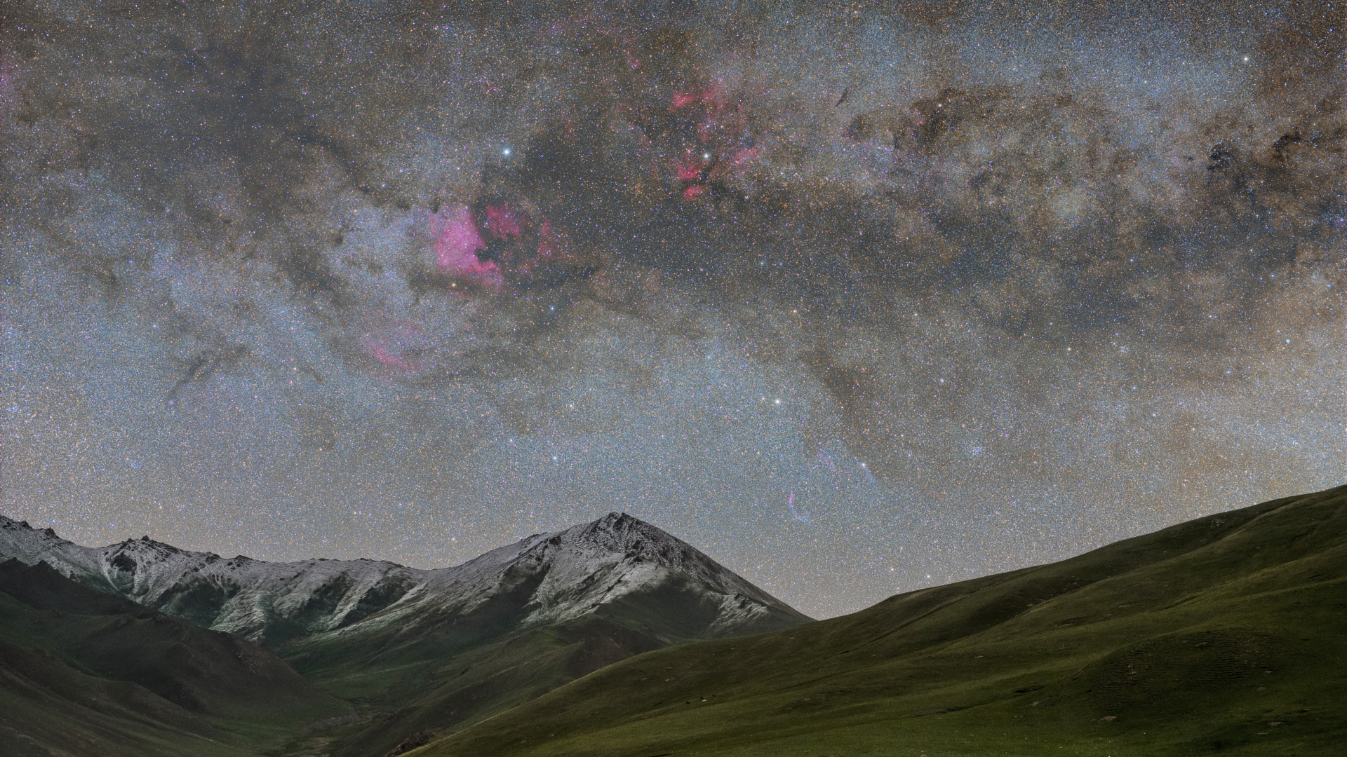 science Les montagnes enneigées sont dominées par un ciel nocturne étoilé avec une immense nébuleuse émettant une lueur rougeâtre.