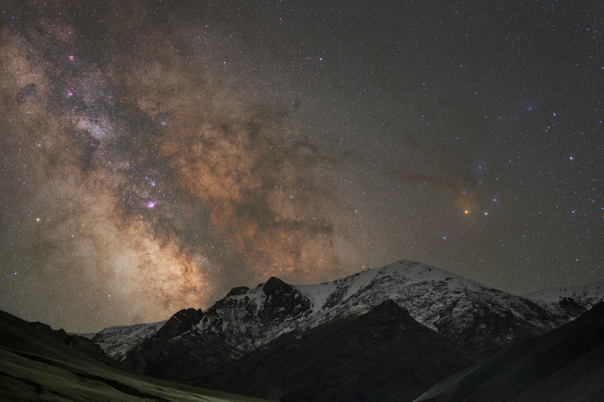 science Au bas de l'image, des montagnes enneigées s'élèvent, tandis que la Voie lactée, dense en étoiles, s'élève vers le ciel.