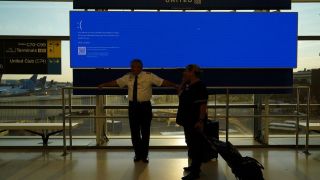 technologie Les employés d'United Airlines attendent près d'un moniteur de départ affichant un écran d'erreur bleu