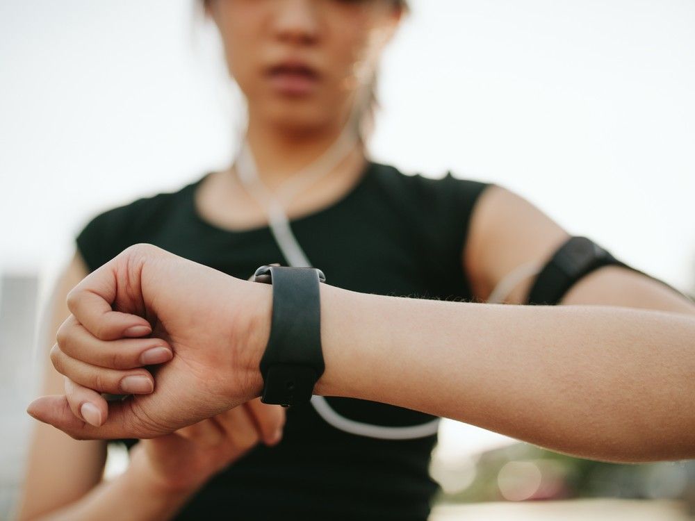 actualités Une jeune femme consulte sa montre connectée pendant qu'elle s'exerce en plein air.