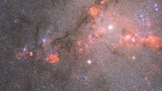 photo du télescope Hubble d'une galaxie remplie d'étoiles entourée de nuages de gaz orange-rouge