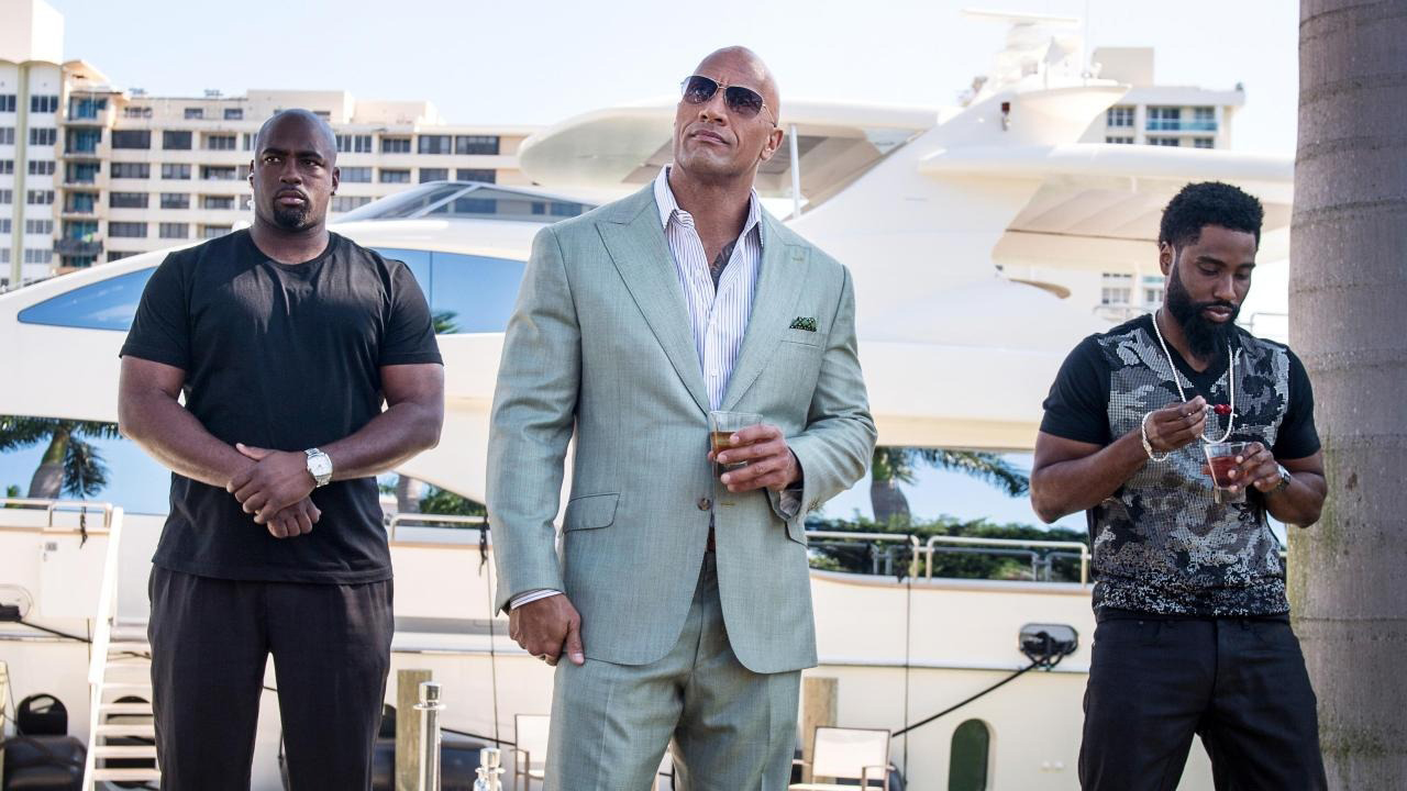 Dwayne "The Rock" Johnson dans un costume bleu avec deux hommes.