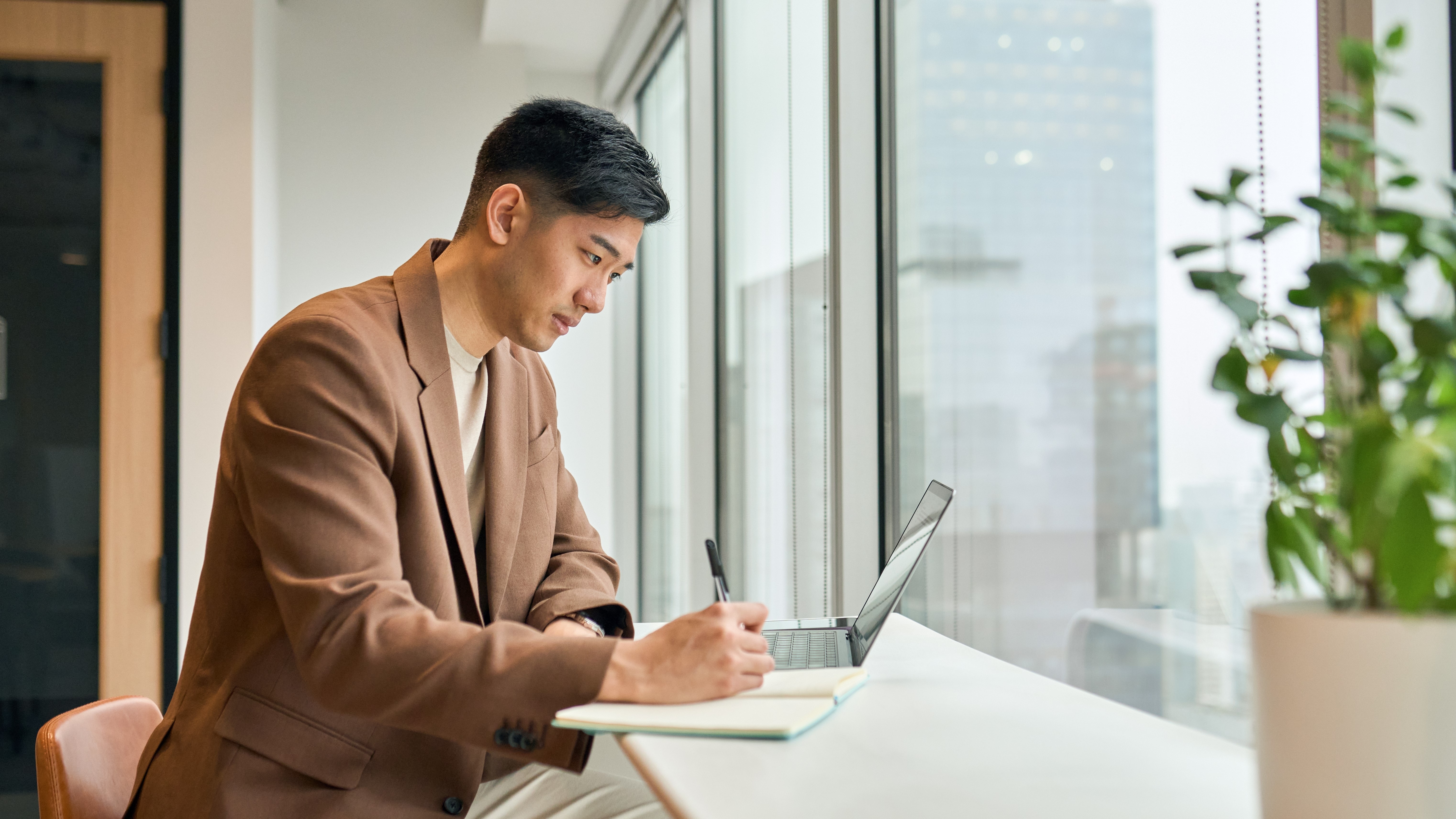 technologie Un jeune homme travaillant sur un ordinateur portable au bureau en prenant des notes