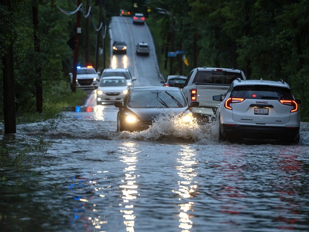 actualités Voitures traversent une route inondée.