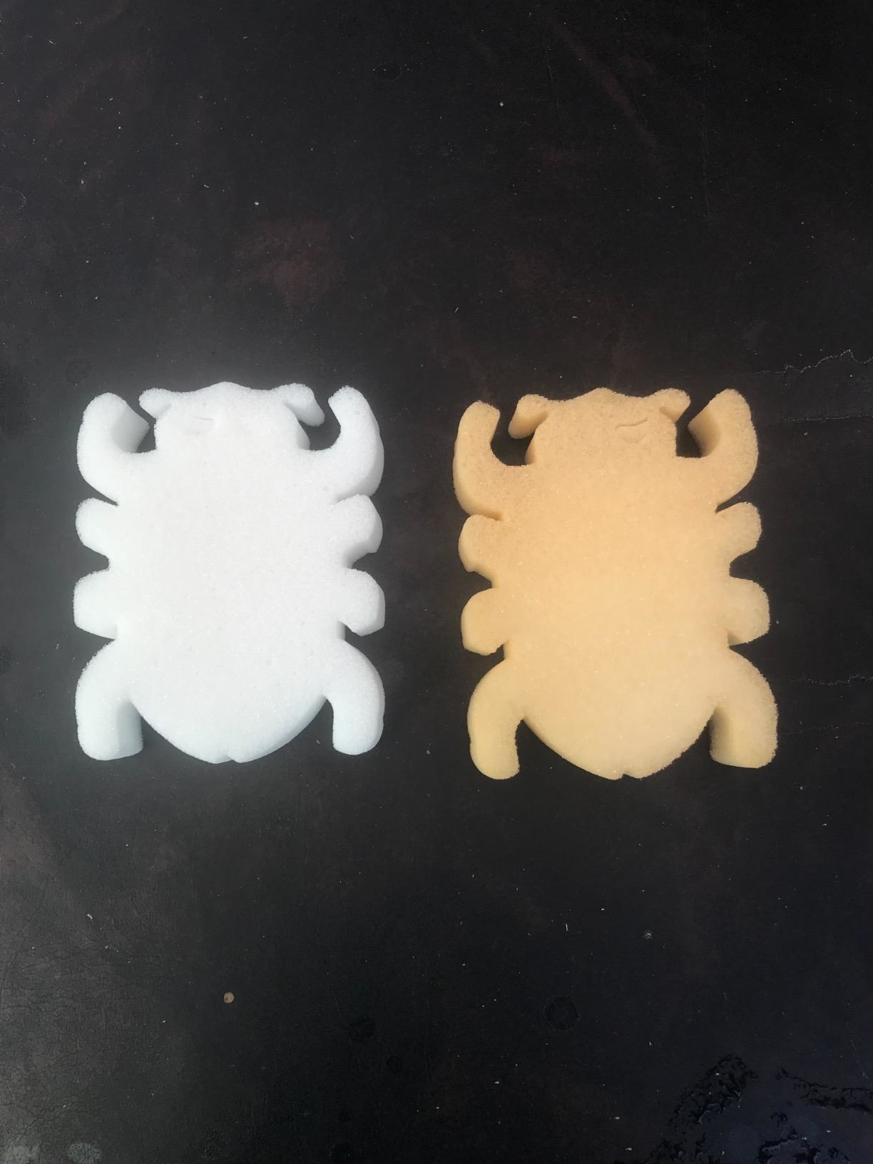 Éponge en forme de bug blanc à côté d'une éponge légèrement orange