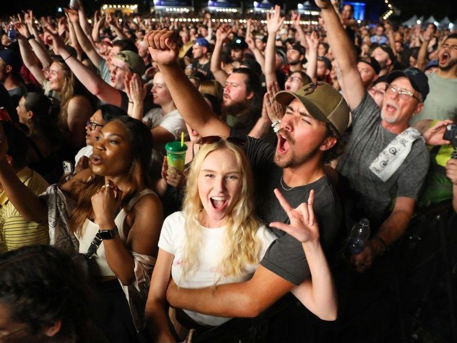 medecine Une fille fait le signe des rockeurs pendant que son partenaire applaudit devant une foule massive